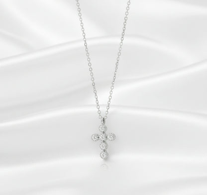 Silver cross necklace with clear stones on a black background