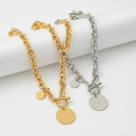 Two gold and silver chain necklaces with round pendants on a blue background