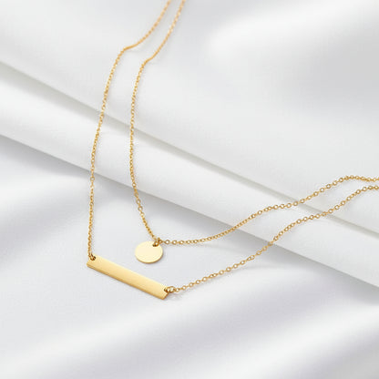 Gold necklace with two pendants on a dark gray background