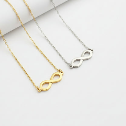 Three necklaces with infinity符号in gold, silver, and rose gold on a beige and white background