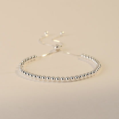 Silver beaded bracelet on a beige background